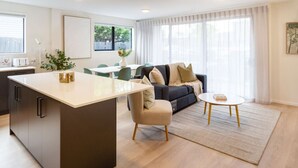 A modern living room with a sofa, a coffee table, and a dining area with chairs and a table.