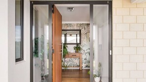 Ein modernes Interieur mit einer Holztür, die zu einem Badezimmer mit Waschtisch und Pflanzen führt.