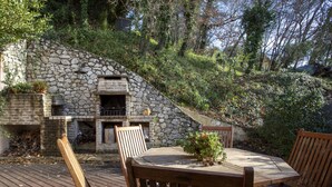 A stone fireplace with a chimney, surrounded by a wooden deck and chairs. - Villa Bellevue by Interhome (Saint Paul de Vence)