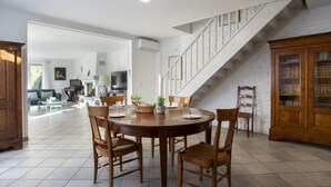 A dining area with a round table, wooden chairs, and a staircase leading to an upper level. - Villa Bellevue by Interhome (Saint Paul de Vence)