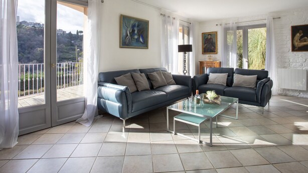 A spacious living room with a large sofa, a coffee table, and a view of the outdoors through a sliding glass door. - Villa Bellevue by Interhome (Saint Paul de Vence)