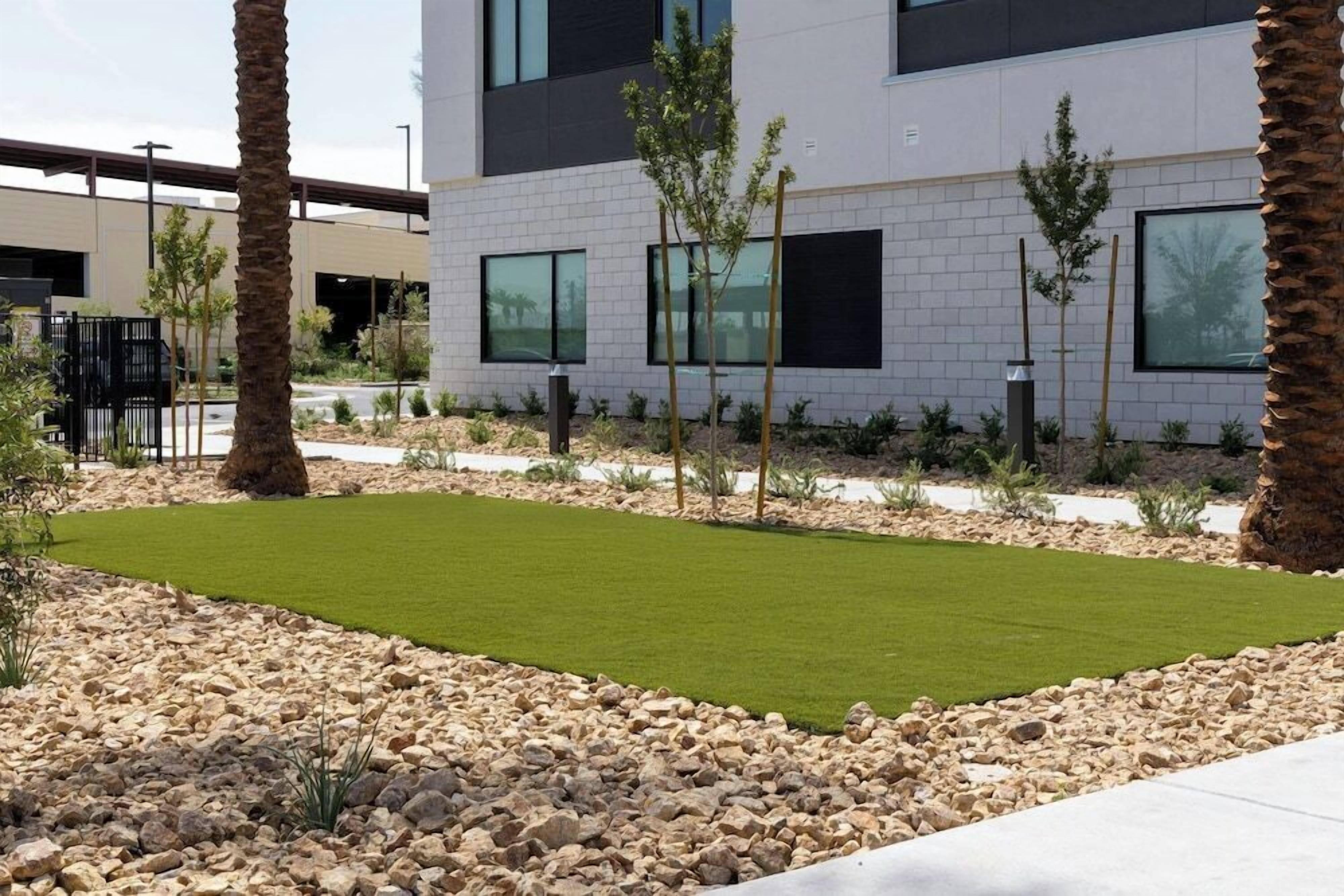 A modern building with a flat roof, large windows, and a landscaped area with grass and rocks.