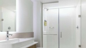 Et moderne badeværelse med et glasbadeværelse, en hvid vask og et toilet.