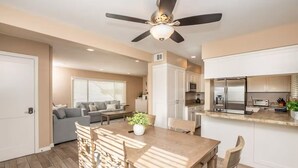 Une cuisine moderne dotée d’un îlot central, un coin repas avec une table et des chaises en bois, et un espace de vie comprenant un canapé et une table basse.
