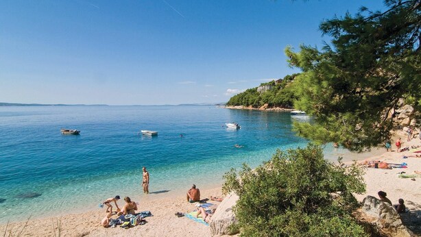 A beach with clear blue water, people sunbathing, and boats. - Cozy apartment in Omis with lake view (Omis)