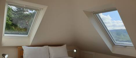 Une chambre à coucher avec un lit, deux tables de chevet et deux fenêtres.