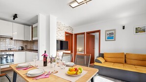 A modern kitchen with white cabinets, a built-in oven, and a dining area with a wooden table set for two.