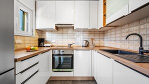 A modern kitchen with white cabinets, a built-in oven, a sink, and a window.