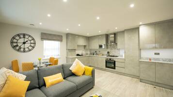 A modern living room with a grey sofa, yellow cushions, and a wall clock.