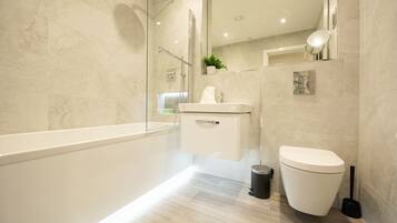 Une salle de bain moderne avec une douche à parois de verre, un lavabo blanc et des toilettes.