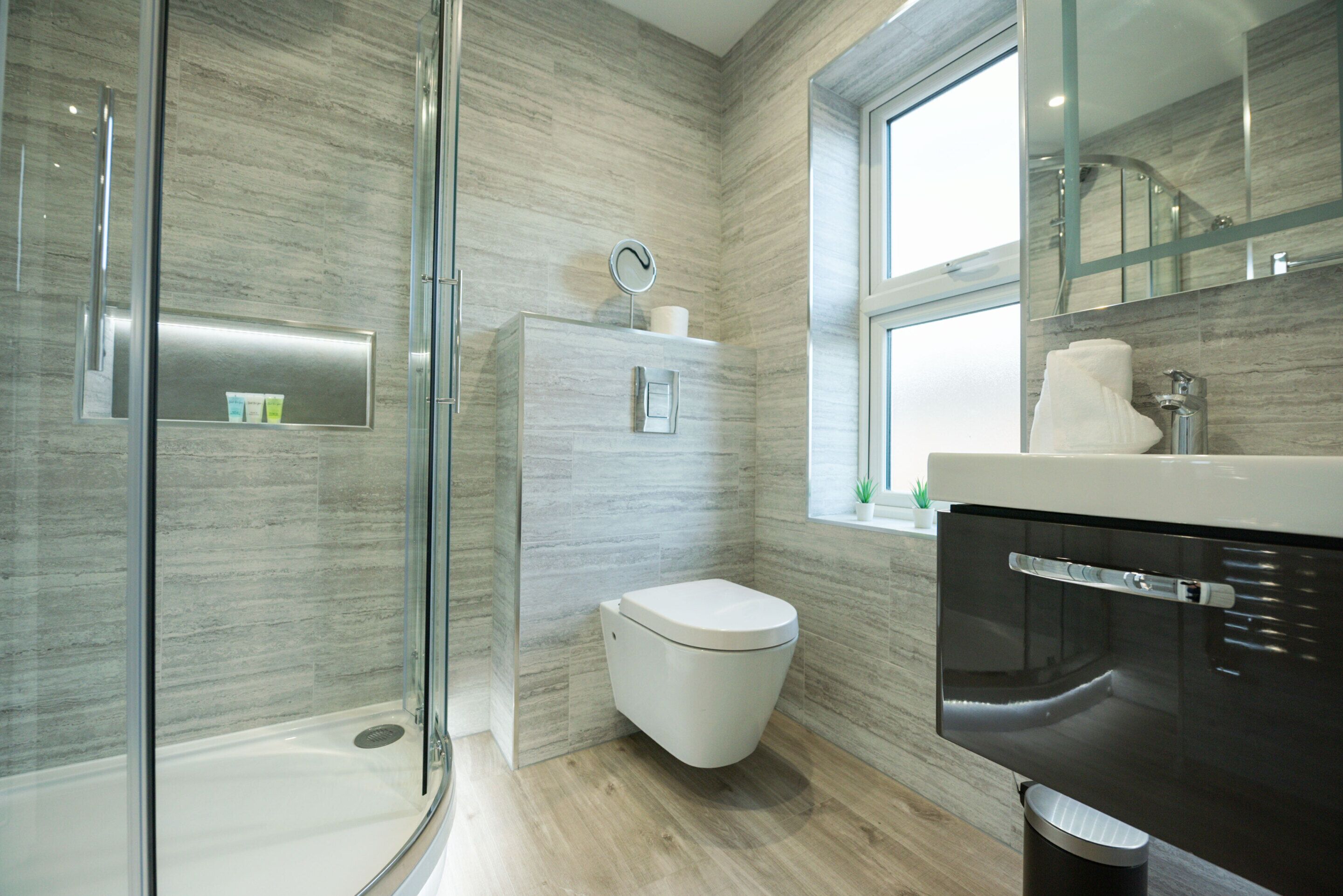 Un baño moderno con cabina de ducha de vidrio, inodoro y lavabo con espejo.