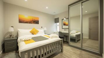 Un dormitorio moderno con cama, mesitas de noche, escritorio y un espejo grande.