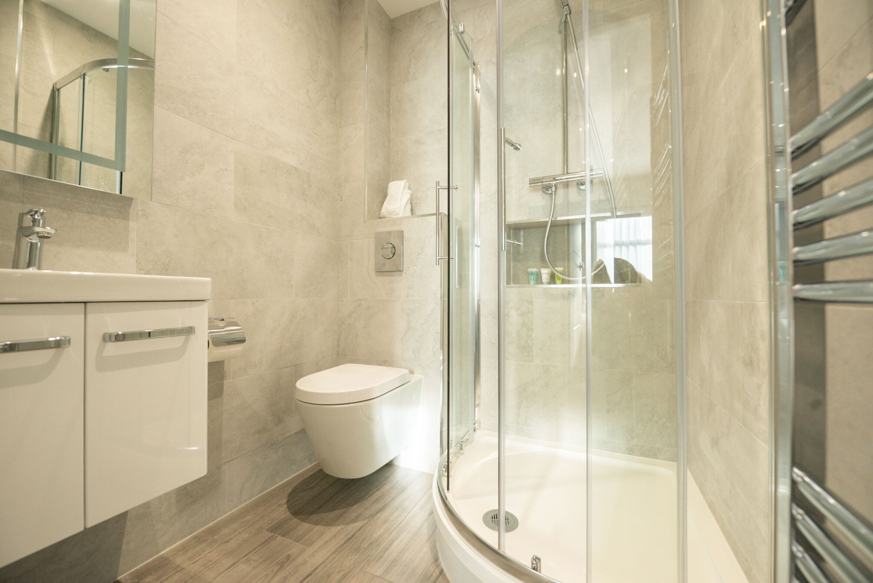 A modern bathroom with a glass-enclosed shower, a toilet, and a vanity with a mirror.