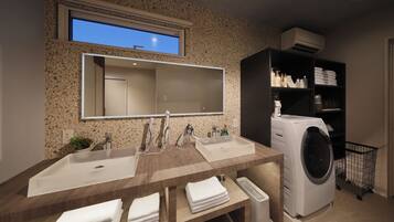 Een moderne badkamer met een grote spiegel, twee wastafels, een ingebouwde wasmachine en een plank met toiletartikelen.
