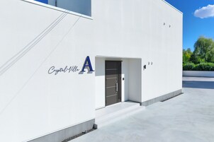 Un edificio moderno con facciata bianca e un grande cartello con la lettera 'A', oltre a un ingresso.