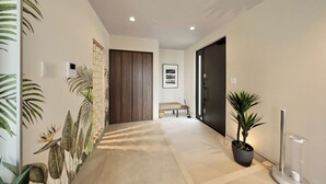 Um corredor com porta de madeira, um banco e um vaso com planta.