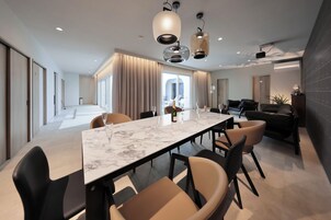 Un comedor moderno con una mesa de mármol, sillas negras y beige, e iluminación colgante.