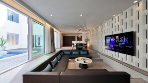 Uma sala de estar moderna com um sofá modular grande, uma mesa de centro e uma televisão de tela plana fixada na parede.