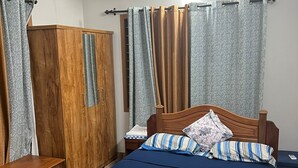 A bedroom with a wooden bed, a wardrobe, a bedside table, and a nightstand. - Two bedroom Villa overlooking Kzuhuppilly Beach (Kochi)