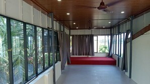 A corridor with large windows, a red carpet, and a ceiling fan. - Two bedroom Villa overlooking Kzuhuppilly Beach (Kochi)