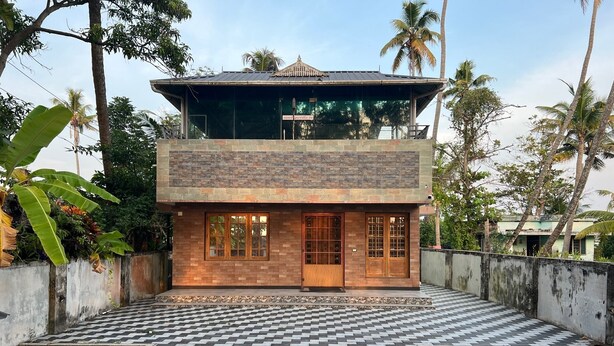 A two-story building with a tiled courtyard, surrounded by palm trees and greenery. - Two bedroom Villa overlooking Kzuhuppilly Beach (Kochi)