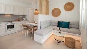 A modern kitchen with white cabinets, a built-in oven, and a dining area with a white table and chairs.
