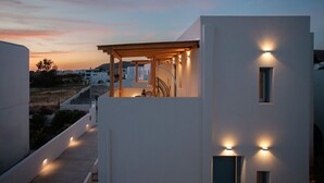 A modern building with a covered outdoor area, a staircase, and a view of the surrounding landscape.