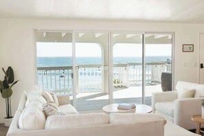 A spacious living room with a large sliding glass door leading to a balcony with a view of the ocean. - Casa Serena, Oceanfront Lodging (El Sauzal)