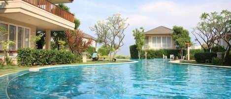 A swimming pool area with a house on one side and a clear sky above.