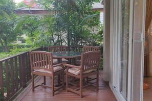 A balcony with a wooden table and chairs, surrounded by a metal railing. - Villa21Chaam (Cha-am)