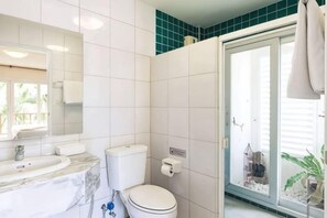 Een badkamer met toilet, wastafel en een glazen deur naar een balkon.
