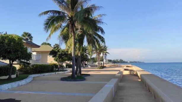 A coastal walkway with palm trees, a concrete barrier, and a view of the sea. - Villa21Chaam (Cha-am)