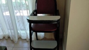 A high chair with a tray attached, positioned near a window with sheer curtains. - Villa21Chaam (Cha-am)