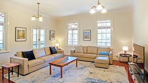 A spacious living room with two sofas, a coffee table, and a rug. There are large windows with white frames and multiple light fixtures. - Rivendell House: Spacious retreat, pet friendly (Shadforth)