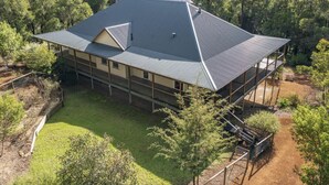 A two-story house with a sloped roof, surrounded by dense trees. - Rivendell House: Spacious retreat, pet friendly (Shadforth)