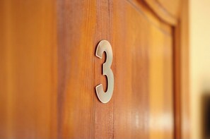 Una puerta de madera con una placa metálica que indica el número 3.