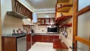 A kitchen with wooden cabinets, a stove, an oven, and a microwave. - Almouahidine Residence (Fes)