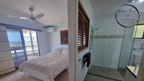 Ein Schlafzimmer mit Bett, Deckenventilator und Blick durch ein Fenster.