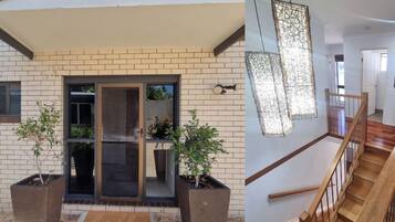 A modern building exterior with a brick facade, large sliding glass doors, and potted plants.