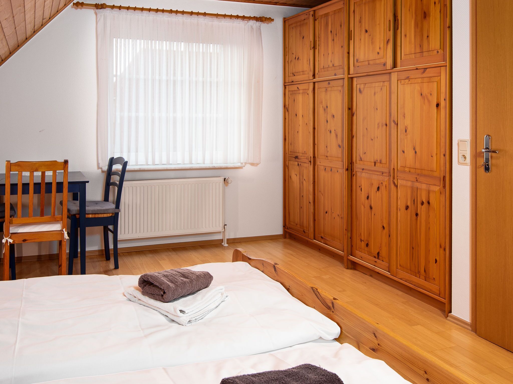 Una camera da letto con un letto, un'armadietto in legno, un termosifone e una finestra con tende.