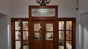 A wooden door with glass panels, a welcome mat, and an emblem above.