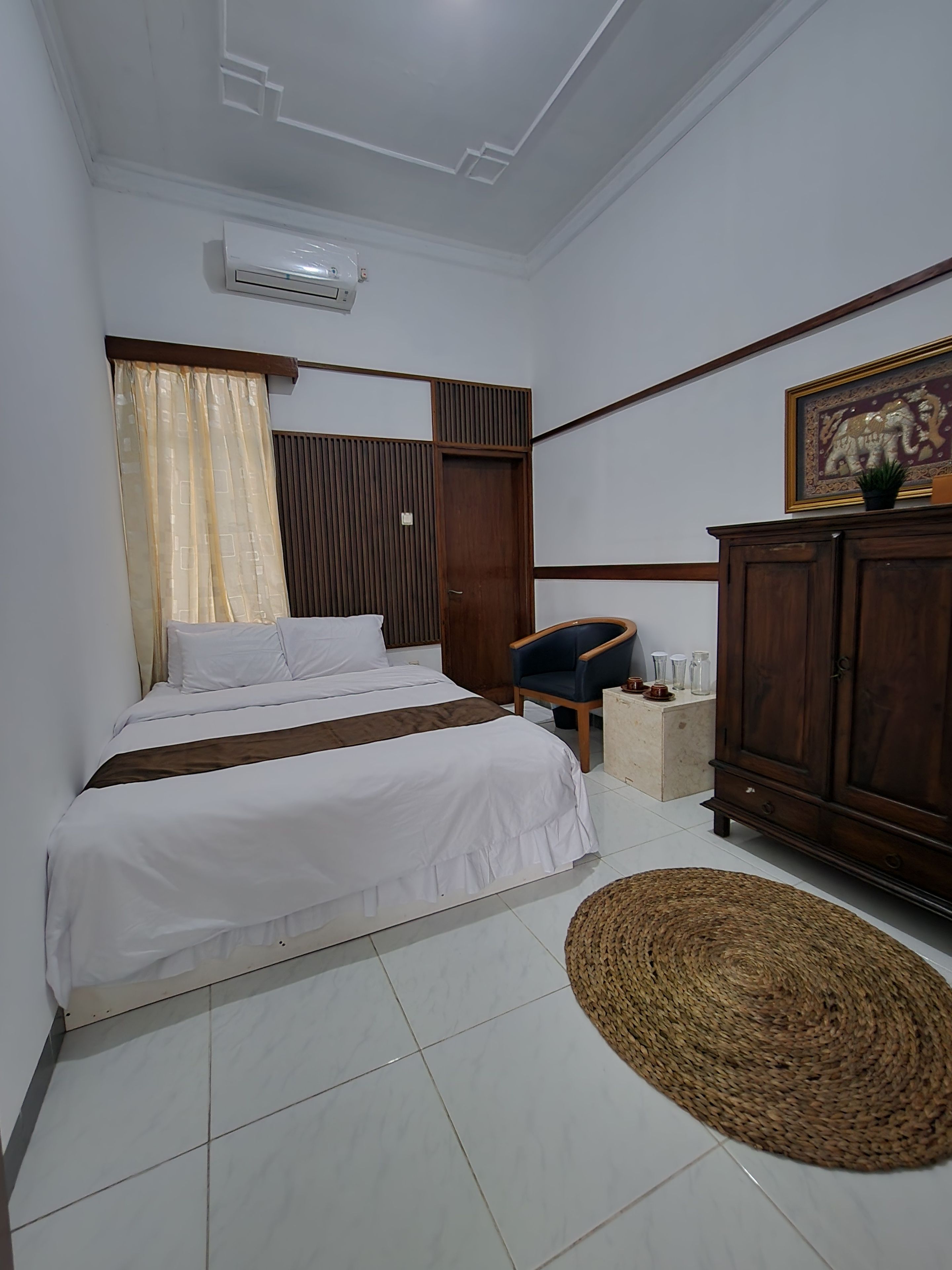 Een slaapkamer met een bed, een stoel, een kledingkast en een decoratief object aan de muur.