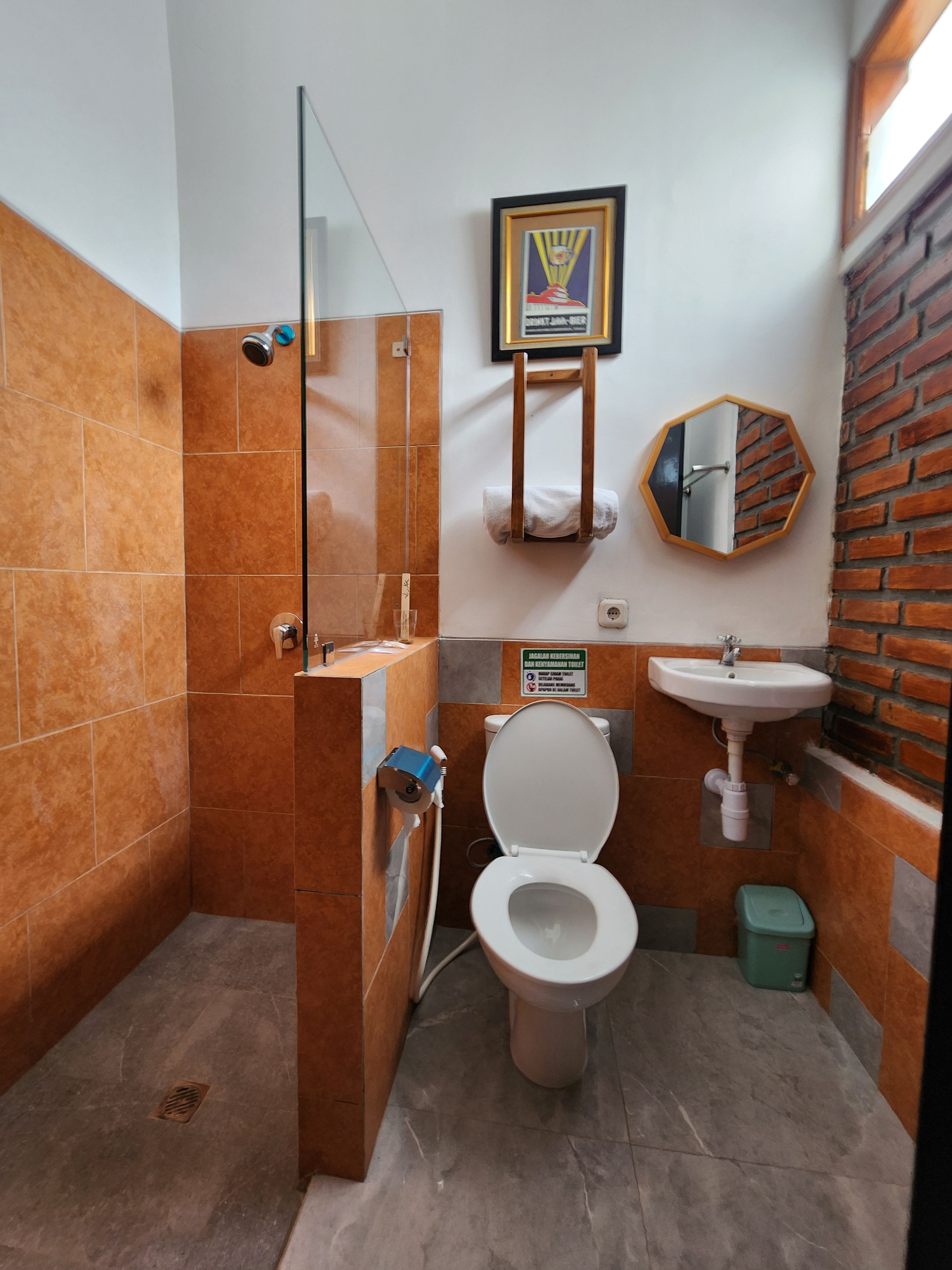 A small bathroom with a glass shower enclosure, a toilet, a sink, and a mirror.