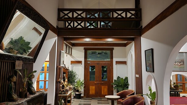 A spacious lobby with a piano, seating area, and a wooden staircase.