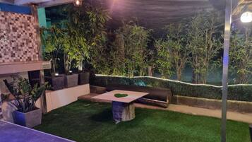 Un espace extérieur aménagé en terrasse, avec un revêtement de gazon synthétique, un coin salon et des plantes en pot.
