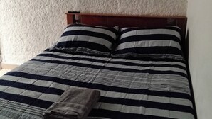 Un lit avec une couvre-lit à rayures et deux oreillers, une tête de lit en bois et un mur à texture.