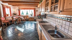 Une cuisine chaleureuse avec des meubles en bois, un pare-feu en carreaux et un coin repas comprenant des chaises et une table en bois.