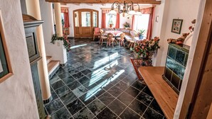 Une salle à manger spacieuse avec un plafond en bois, un lustre et un sol carrelé.