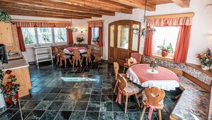 Un coin repas chaleureux avec un plafond en bois, une table ronde entourée de chaises et un banc.