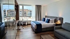 Ett modernt hotellrum med en stor säng, en soffa, ett skrivbord och utsikt över stadsbilden.
